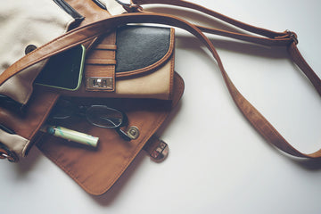 Open Handbag with Glasses, Wallet, Phone, and Lip Balm Spilled Out, Showcasing Everyday Functional Items