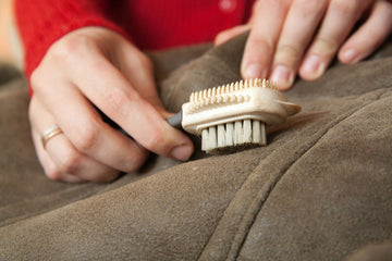 A person removing ink from a brown leather using a tool