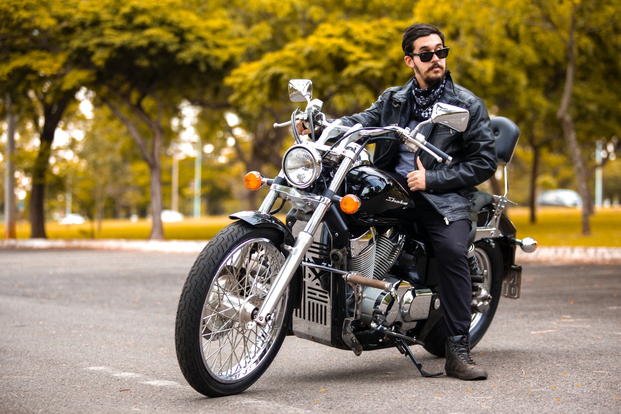 man wearing leather jacket and sitting on bike