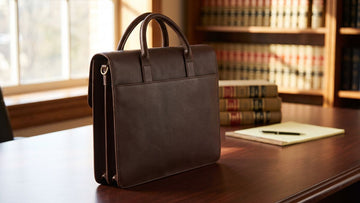 Structured leather briefcase standing upright on a polished table in a law office