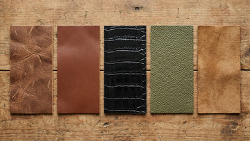 Five leather swatches showing different types of leather textures from full-grain to suede on a wooden surface
