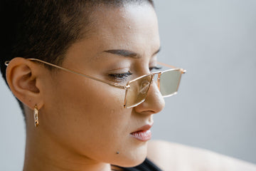 Woman Wearing Gold Hoop Earrings and Stylish Glasses with a Close-Cropped Hairstyle