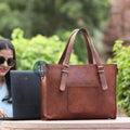 Woman Working on a Laptop Outdoors with a Leather Laptop Tote Bag Featuring Brass Buckles Nearby