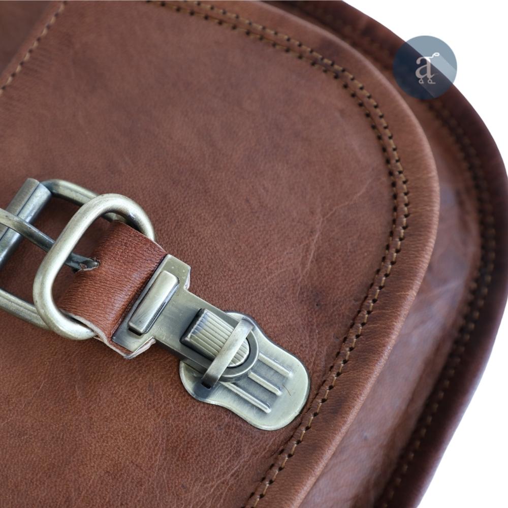 Close-Up of Brown Leather Saddle Purse Showing Metal Buckle, Highlighting Detailed Stitching and Textured Leather Finish
