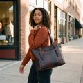 Woman in a rust sweater on a shopping street carrying the Anuent dark brown leather purse on her shoulder