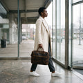 Woman carrying The Convertible leather laptop briefcase by its top handles in an office lobby