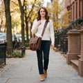 Woman walking down a brownstone sidewalk wearing The Digital leather laptop messenger bag crossbody