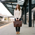 Woman on a train platform holding The Digital leather laptop messenger bag in front of her by the handle