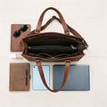 Flat lay of the open brown leather laptop tote bag with a laptop, tablet, notebook and sunglasses