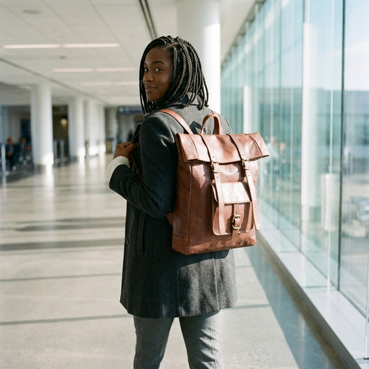 Woman wearing The Adventurer brown leather roll-top backpack in an airport concourse