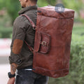 A Man Carrying The Yachtsman Duffle As A Backpack, Wearing A Brown Shirt With Elbow Patches And Jeans