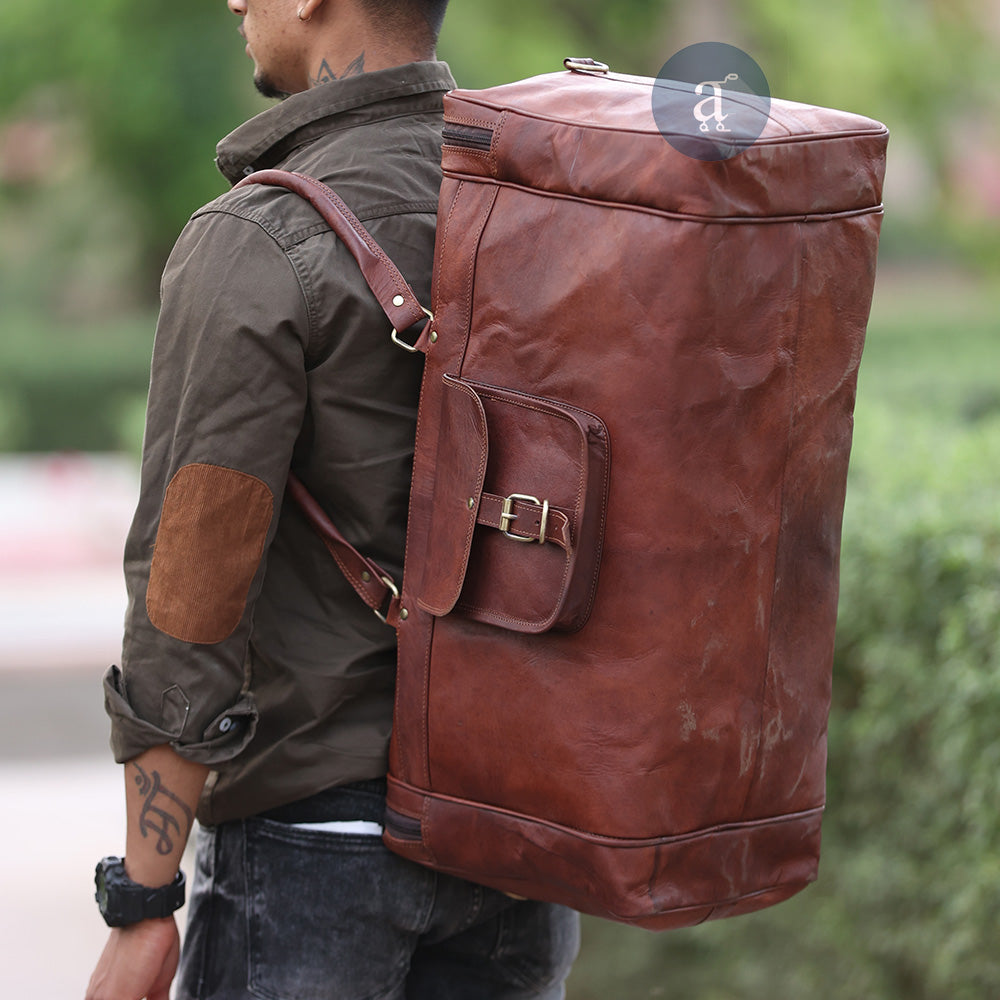 A Man Carrying The Yachtsman Duffle As A Backpack, Wearing A Brown Shirt With Elbow Patches And Jeans